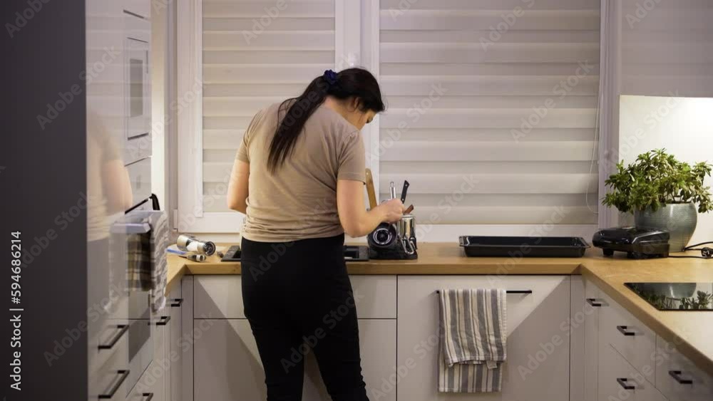 Woman washing the dishes in the kitchen after the long day at work Woman washing the dishes in the kitchen after the long day at work