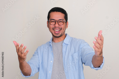 Adult Asian man looking camera showing excited expression with both hands want to embrace someone photo