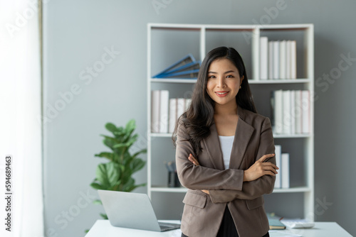 Asian businesswoman smiling confidently A successful entrepreneur in the financial business professional company executive wearing a suit standing with arms crossed in the office.