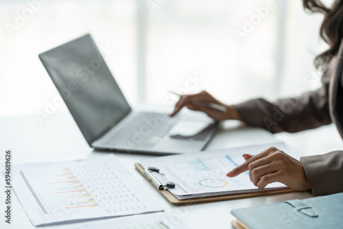 Asian businesswoman, online freelancer, confident investor working at laptop computer and pointing to graph showing financial growth. e-commerce management concept marketing.