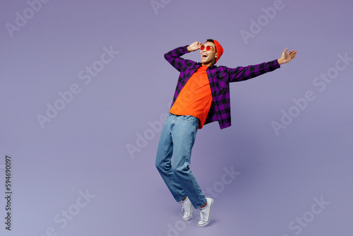 Full body young man of African American ethnicity wear casual shirt orange hat stand on toes leaning back with outstretched hand dance isolated on plain pastel purple color background studio portrait.