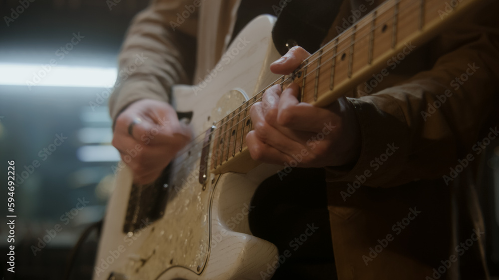 Hands close up shot of musician playing on electric guitar in sound recording studio. Professional musical instruments and equipment. Rock band records song for new album. Music production concept.