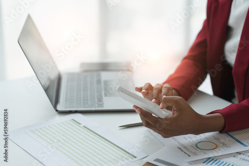Project revenue and profit accounting African american businesswoman working with laptop financial charts and graphs calculating financial income with calculator at office desk.