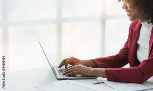African american businesswoman sitting and recording data details in financial business Online marketing plan to process and send emails for meeting preparation sitting at laptop desk in office. photo