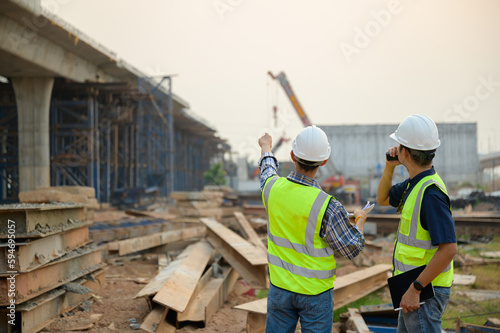 A road construction engineer with civil engineer to supervise new road construction and inspect construction site site.