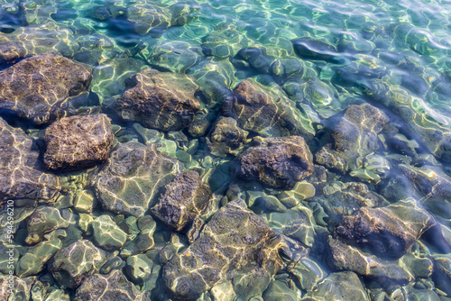 Gleaming transparent aquamarine sea water with rocks underwater