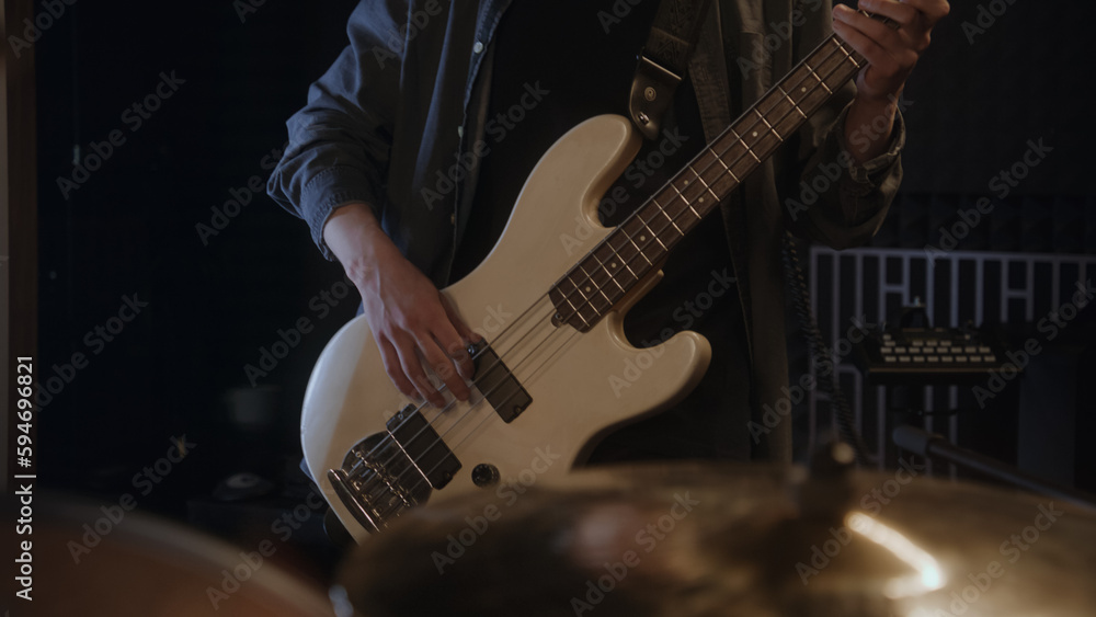 Obraz premium Professional musicians records song in sound recording studio. Male guitarist plays the electric guitar. Close up of drummer playing a drum kit. Work in music recording room. Music production concept.