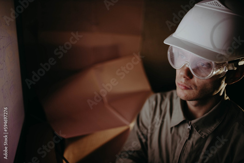 engineer architect in a hard hat with blueprints designs on a computer