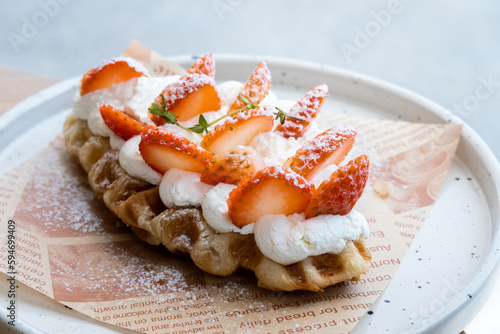 Yummy waffles with whipped cream, strawberries and caramel syrup on table, top view shot