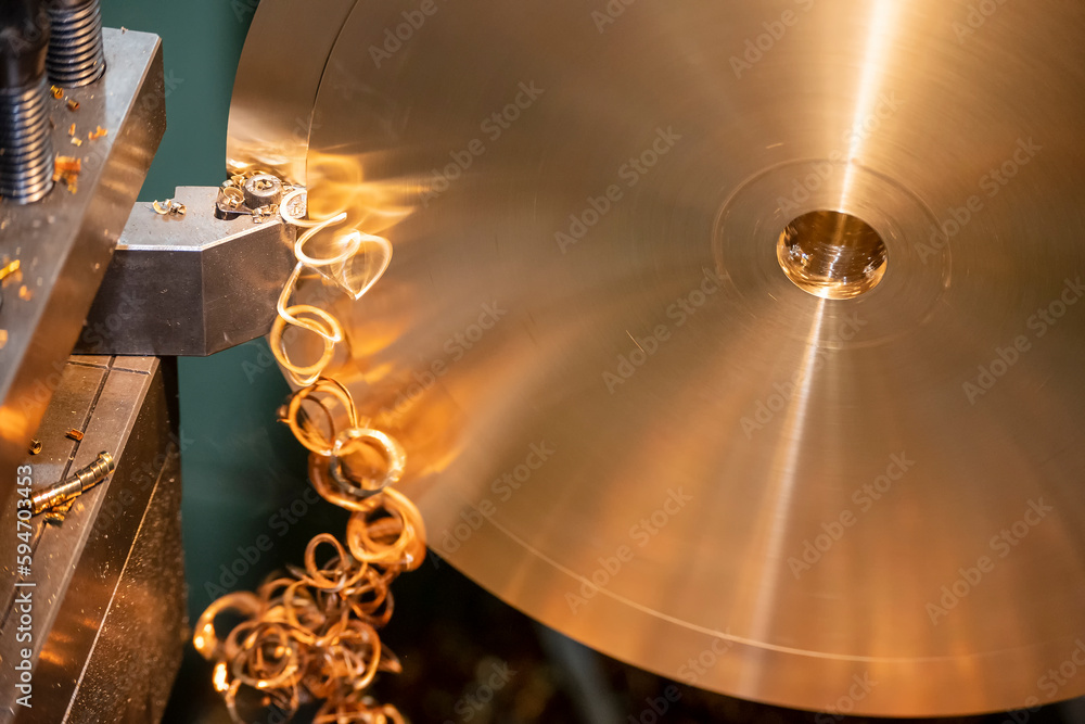 Close-up the lathe machine finish cutting the brass disk parts by lathe tools. Close-up the lathe machine finish cutting the brass disk parts by lathe tools.