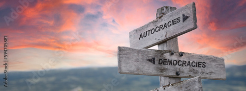 autocracies democracies text quote on wooden sign outdoors in nature. pink dramatic sunset background.