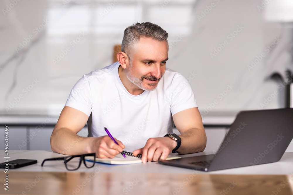 Mid age man working on laptop write at home Mid age man working on laptop write at home