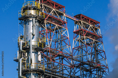 Oil refining plant. Technological equipment for the production of fuel components. White smoke escapes into the atmosphere from the production equipment at the refinery. Factory equipment.