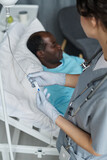 Vertical image of nurse in uniform making dropper for elderly patient in hospital ward