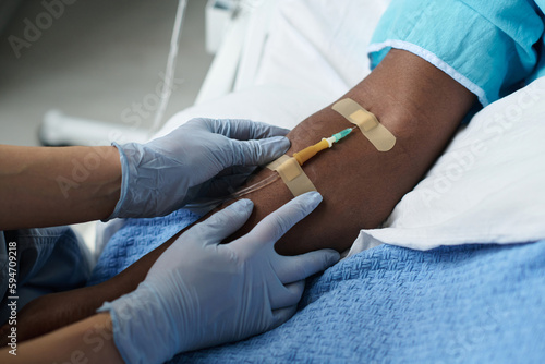 Tableau sur toile Close-up of nurse inserting catheter in arm of patient while he lying on bed in