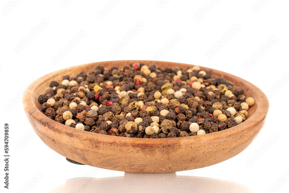 A mixture of four peppercorns on a wooden saucer, macro, isolated on a white background. A mixture of four peppercorns on a wooden saucer, macro, isolated on a white background.