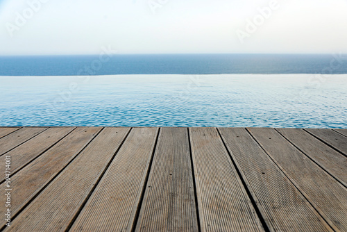 bordo in legno di una piscina che si proietta a strapiombi sul mare photo