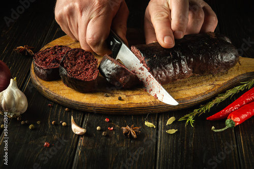 A knife in the cook's hand for cutting blood sausage for a very tasty dinner. Cooking a national dish with spices at home