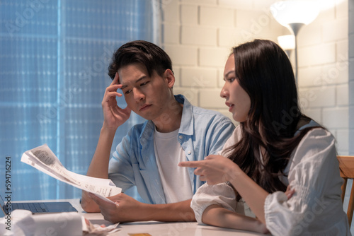 Stressed and confused Asian couple calculating expenses on invoices. photo