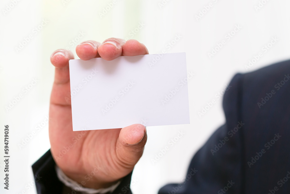 Close up businessman in black suit holding white empty name card Close up businessman in black suit holding white empty name card