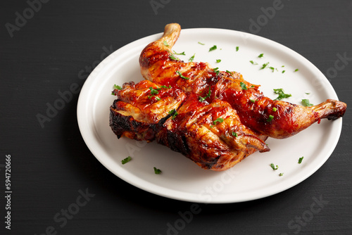 Homemade Spatchcocked Grilled Piri-Piri Chicken with Parsley on a Plate, side view. Copy space.
