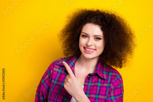 Portrait of gorgeous pretty youngster woman directing finger empty space announce coming soon season discount isolated on yellow color background