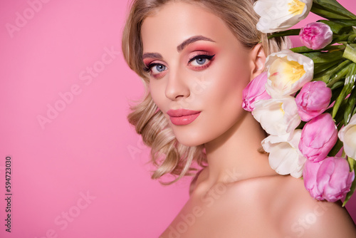 Stunning girl model studio portrait posing over decorated tulips backdrop bright makeup isolated pink pastel background