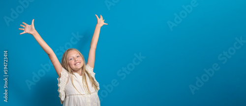 Happy childhood. A smiling young girl raises her hands to the top. isolated. Background blue. banner. copy space