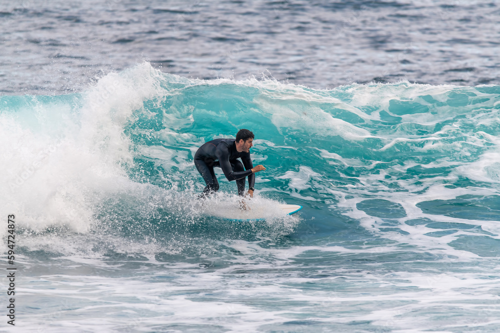 Athletic young man surfing inside a wave in a wetsuit in Tenerife Athletic young man surfing inside a wave in a wetsuit in Tenerife