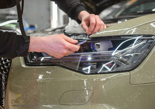 The process of installing a protective polyurethane film for paint on the front headlight of a car. PPF is a polyurethane film that helps protect glass and metal from scratches. Selective focus. 
