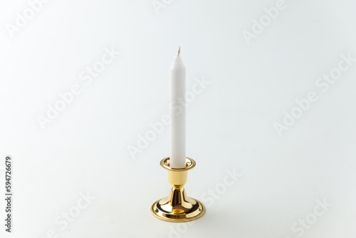 white candle inside golden candlestick on a white background flame lamp steel metallic fire