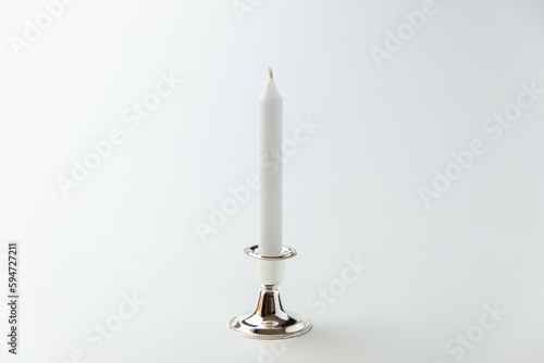 white candle inside silver candlestick on white background flame lamp fire steel metallic