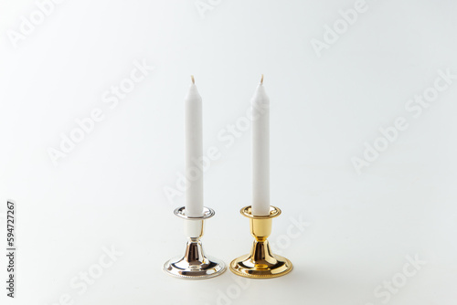 white candles inside elegant candlesticks on a white background flame lamp fire steel metallic
