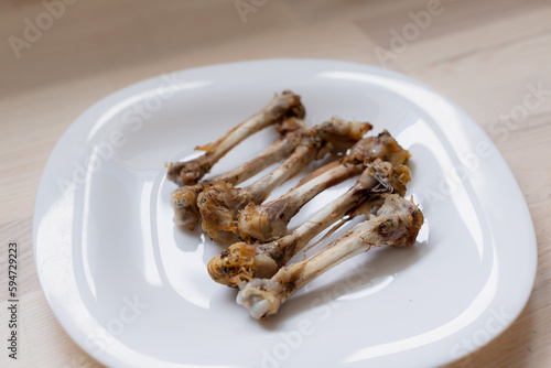 Multiple chicken bones on a white plate