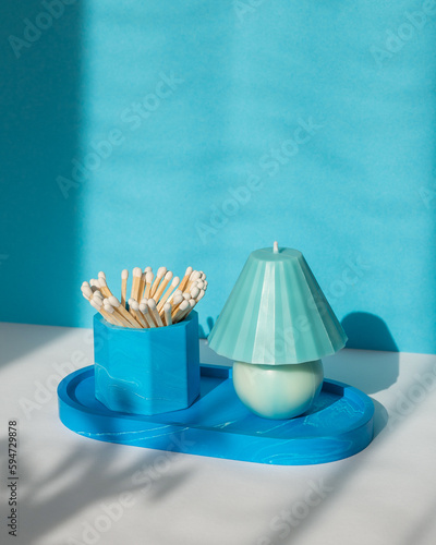 A handmade candle and a glass with matches on a blue-white background.
