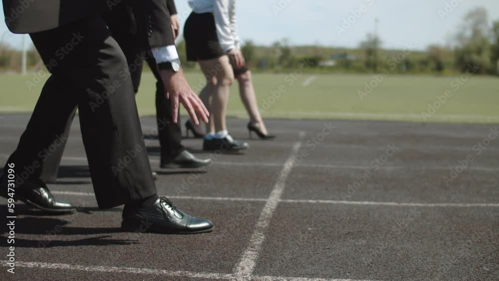 Concept of business competition, goals, achievements. Businessmen stand on starting line of stadium preparing for the race, close-up of the legs Concept of business competition, goals, achievements. Businessmen stand on starting line of stadium preparing for the race, close-up of the legs
