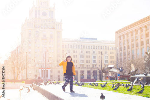 a happy boy runs across the square with birds in the historical center of the city, enjoying the holidays and good weather photo