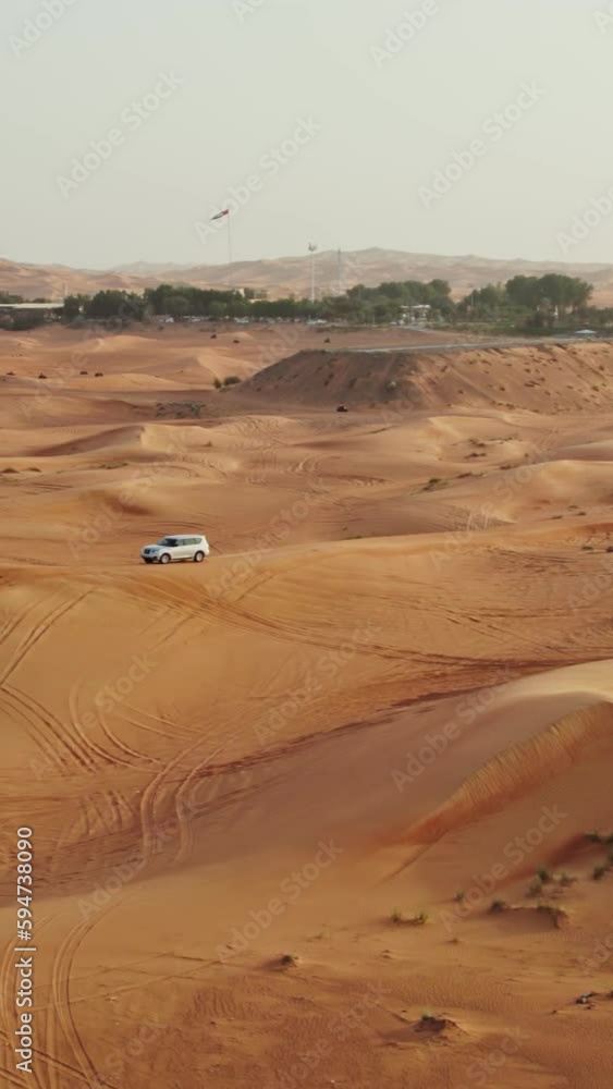 Cars drive off-road on the red sand dunes of the desert with sparse vegetation among the sand, drone video Cars drive off-road on the red sand dunes of the desert with sparse vegetation among the sand, drone video