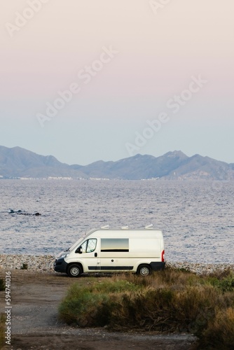 White van parked on the beach with a tranquil sea in the background