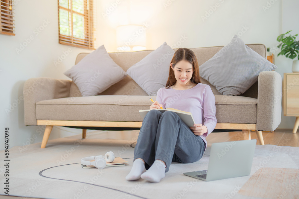 Young woman working and writting on her note book at her home. Work from home concept. Young woman working and writting on her note book at her home. Work from home concept.