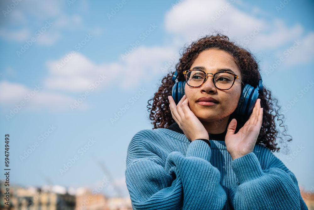 Calm Hispanic woman in headphones on sunny street Calm Hispanic woman in headphones on sunny street