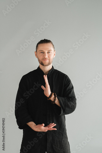 A man in black kimano practicing qigong energy exercises indoors photo