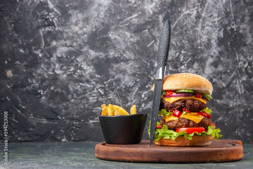 Tasty homemade sandwich tomatoes fries gray knife on wooden cutting board on dark color background with free space photo