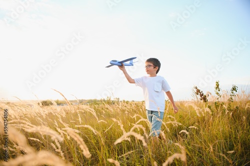 The kid runs with a toy plane. Son dreams of flying. Happy child  boy  runs on the sun playing with a toy airplane on the summer field