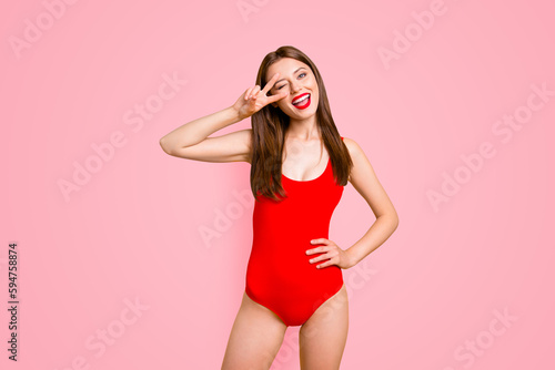 Party mood Portrait of foolish playful girl gesturing v-sign near winking eye showing tongue out looking at camera isolated on vivid yellow background © deagreez
