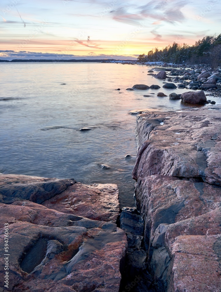 Obraz premium Stunning coastal shoreline, featuring a rocky shore and tranquil waters, with orange sunset