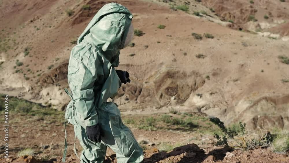 An ecologist, a biologist in a protective suit is studying the area to conduct soil quality control. Possibly in a toxic hazardous area with air pollution An ecologist, a biologist in a protective suit is studying the area to conduct soil quality control. Possibly in a toxic hazardous area with air pollution