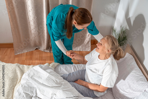Nurse helping an elderly woman at her home. Solicitous professional medical female staff caring in a geriatric institution with a senior patient. Lifestyle