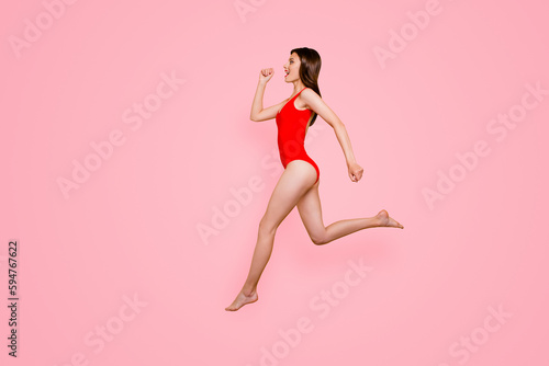 People life energy concept. Full-size portrait of fit sporty girl jumping over in the air isolated on yellow background with copy space for text