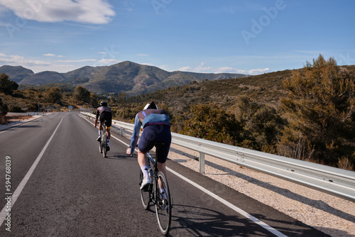 Two professional cyclists are riding.Men in full cycling gear are training on a mountainous road in Spain, surrounded by breathtaking views.Alicante region